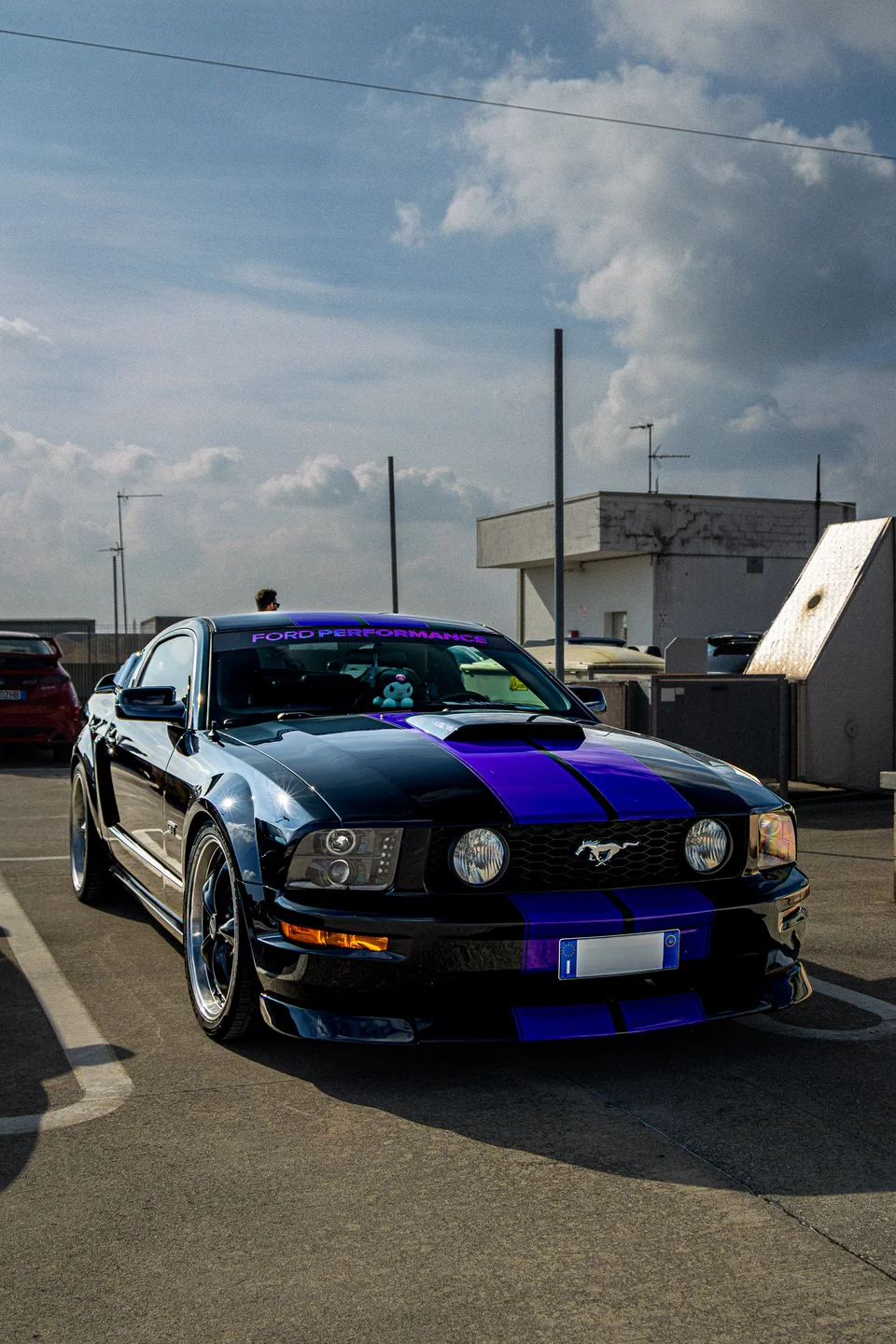 Ford Mustang nera con strisce viola fotografata a un raduno
